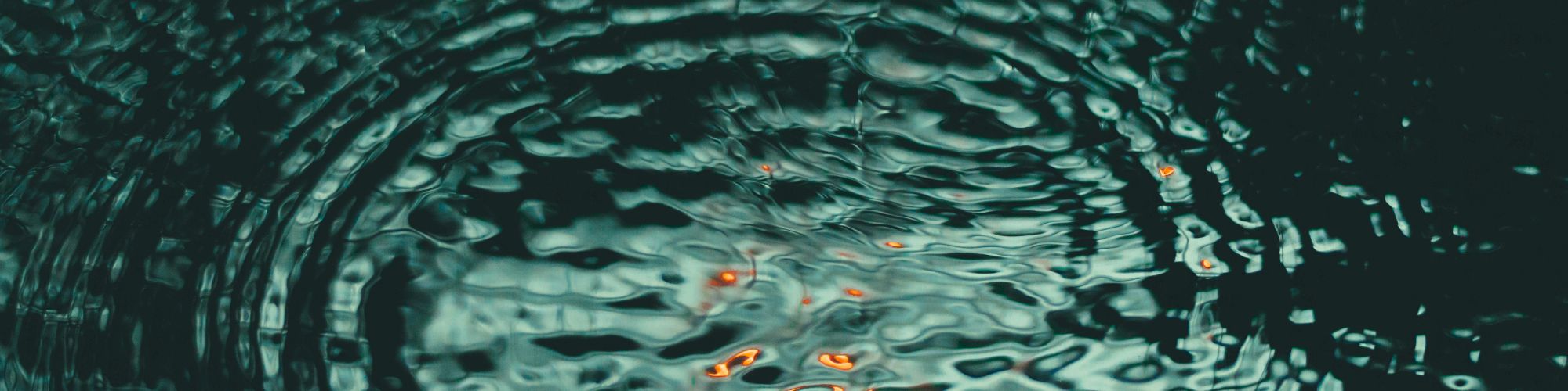 An abstract teal water swirl with ripples and floating glowing orange embers drifting through the current.